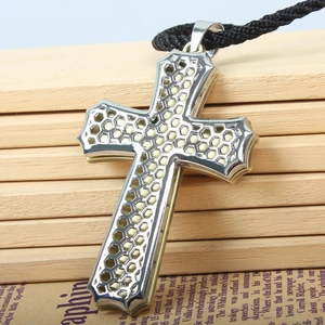 Macro shot of silver stainless steel cross pendant with modern honeycomb hollow pattern