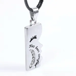 Macro shot of silver metal pendant with 'Has been certified' text and crescent diamonds