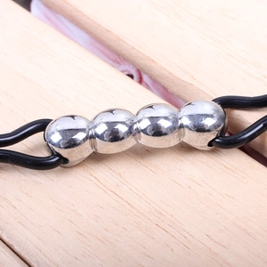 Macro shot of a silver four-bead metal charm on a black double-cord bracelet band