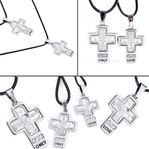 Detail of cross pendant featuring skull relief and inlaid zircons on a black cord