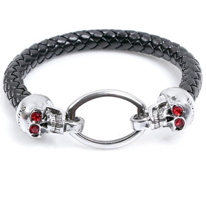 Braided black leather bracelet featuring dual silver skulls with red ruby-style crystal eyes