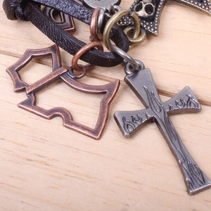 Macro detail of antique bronze cross and skull pendants on a vintage leather cord necklace