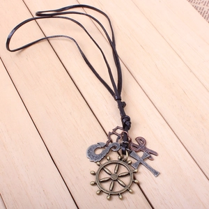 Detail of vintage ship wheel and scissor pendants on a long black leather cord necklace