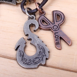 Detail of vintage anchor and bronze scissors charm with LOVE engraving on leather cord