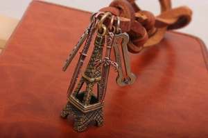Close-up of bronze Eiffel Tower, dagger and bone pendants on brown leather cord