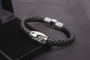 Detail of men's black braided leather bracelet with silver lightning bolt magnetic clasp