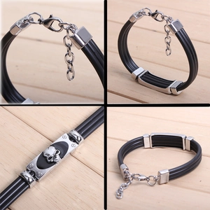 Detail of black braided punk bracelet with silver skull charm and lobster clasp closure