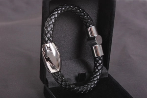 Macro detail of men's leather bracelet showing silver lightning bolt magnetic clasp