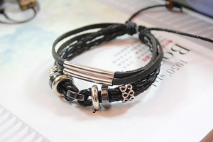 Detail of multi-layer black braided leather bracelet with silver metal tubes and pull cord