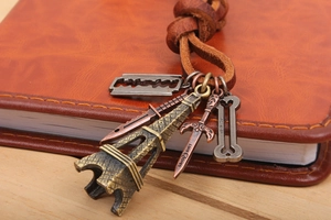 Macro detail of bronze Eiffel Tower charms on a braided brown leather cord pendant