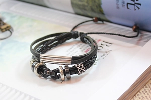 Detail of multi-layer black leather woven bracelet with silver metal beads and wood charms