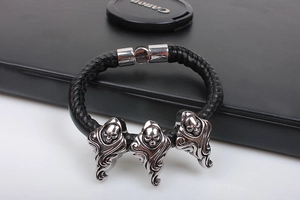 Close-up of black braided leather bracelet with silver triple skull punk charms and magnetic clasp