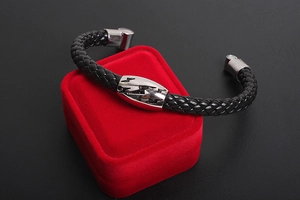 Detail of men's braided black leather bracelet with lightning bolt metal charm on a red box