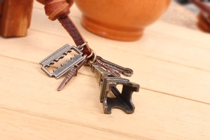 Detail of Eiffel Tower and alloy blade charms on a brown leather cord necklace