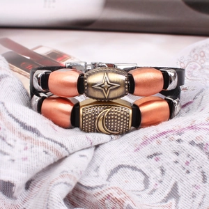 Macro detail of star and moon charms on braided leather bracelets with metallic finish