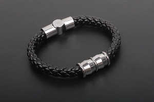 Macro detail of men's braided black leather bracelet with silver metallic hardware