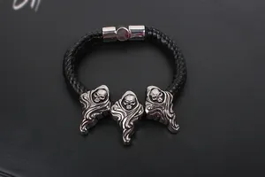 Detail of gothic leather bracelet featuring three silver skull charms and magnetic clasp