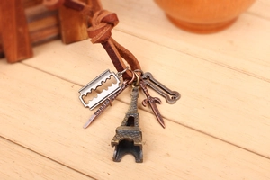 Detail of vintage leather necklace featuring Eiffel Tower and sword pendants