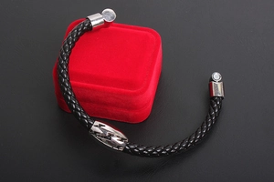 Macro shot of a black braided leather men's bracelet with a silver lightning bolt metal charm