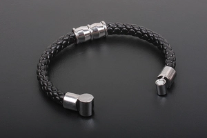 Detailed macro view of the silver magnetic cylinder clasp on a black braided leather bracelet