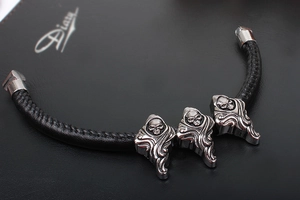 Detail view of punk style braided leather bracelet with silver skull charms on diary