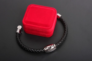 Close-up of black braided leather bracelet with lightning pattern metal buckle on a gift box