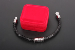 Macro detail of men's black braided leather bracelet with silver magnetic steel clasp
