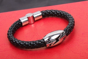 Macro view of men's black braided leather bracelet with lightning bolt metal charm