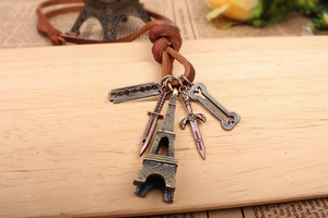 Close-up of vintage bronze Eiffel Tower and dagger pendants on a brown leather necklace cord