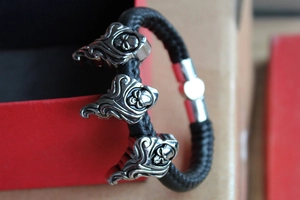 Macro detail of men's punk leather bracelet with silver skull charms and magnetic clasp
