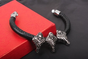 Close-up of black leather punk bracelet with hooded skull metal charms on red box