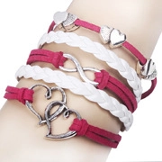 Détail d'un bracelet tressé multicouche rose et blanc avec breloques cœur et infini en argent