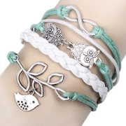 Détail de bracelet multicouche avec cordons tressés verts, breloques chouette et feuilles