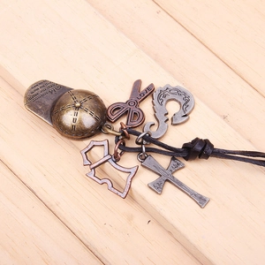 Detail of vintage bronze baseball cap and scissors charms on black leather necklace cord