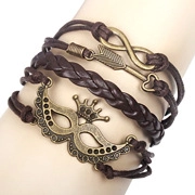 Détail d'un bracelet multicouche en cuir PU avec des breloques flèche et couronne en bronze