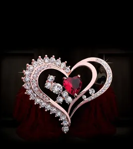 Détail de la broche en forme de cœur en or rose avec zircon rouge et strass brillants