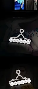 Détail de la broche cintre en métal argenté avec perles blanches et strass étincelants