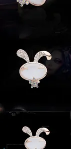 Dettaglio della spilla a coniglio in oro rosa con pietra occhio di gatto bianca e strass
