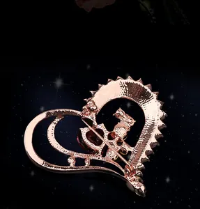 Détail macro d'une broche cœur en or rose avec cristal rouge et motif de chat