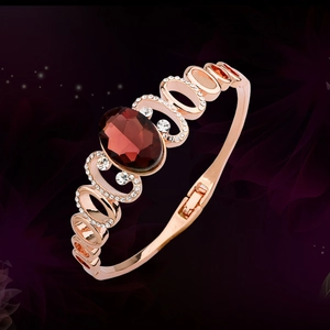 Elegant rose gold bracelet featuring a large oval red stone and crystal accents