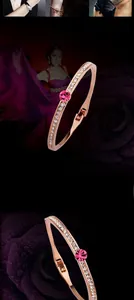 Rose gold bracelet with a pink center stone and white crystals on a rose background