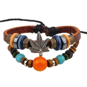 Détail d'un bracelet multicouche en cuir vintage avec breloque feuille d'érable et perles