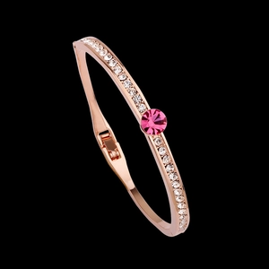 Rose gold open bangle with white crystals and large magenta center stone on black