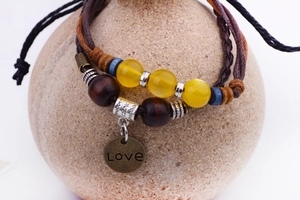 Détail du bracelet multicouche en cuir tressé avec perles et pendentif Love