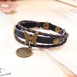 Détail d'un bracelet multicouche en cuir vintage avec papillon en bronze et arbre de vie