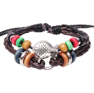 Détail d'un bracelet multicouche en cuir avec pendentif poisson et perles en bois coloré