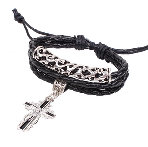 Détail d'un bracelet en cuir tressé noir avec tubes en métal argenté et charm de croix