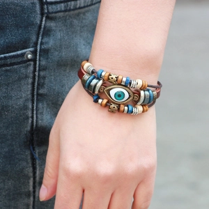 Bracelet multicouche en cuir fait main avec œil protecteur et perles sur fond denim