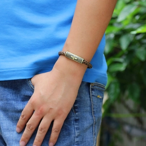 Vintage woven leather bracelet with bronze eagle charm worn on wrist in a casual style