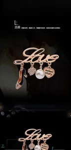 Détail de la broche Love dorée avec talons hauts, pendentifs en cœur et perle blanche